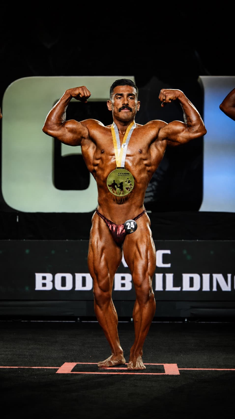 Coach Chris posing on stage during a bodybuilding competition
